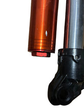Load image into Gallery viewer, Close-up of a metal mechanical component with an anodized orange-red cylindrical section and a black plastic or cast-metal joint, placed on a wood surface.