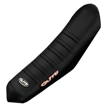 Load image into Gallery viewer, Black motorcycle or scooter seat cover with a carbon fiber texture, featuring a red and white GUTS logo on the side and a smaller white GUTS emblem near the end.
