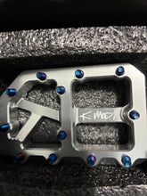 Load image into Gallery viewer, A close-up of a metallic silver metal plate with cutouts and blue iridescent screws, featuring a custom engraving that reads 'K-Mod'.
